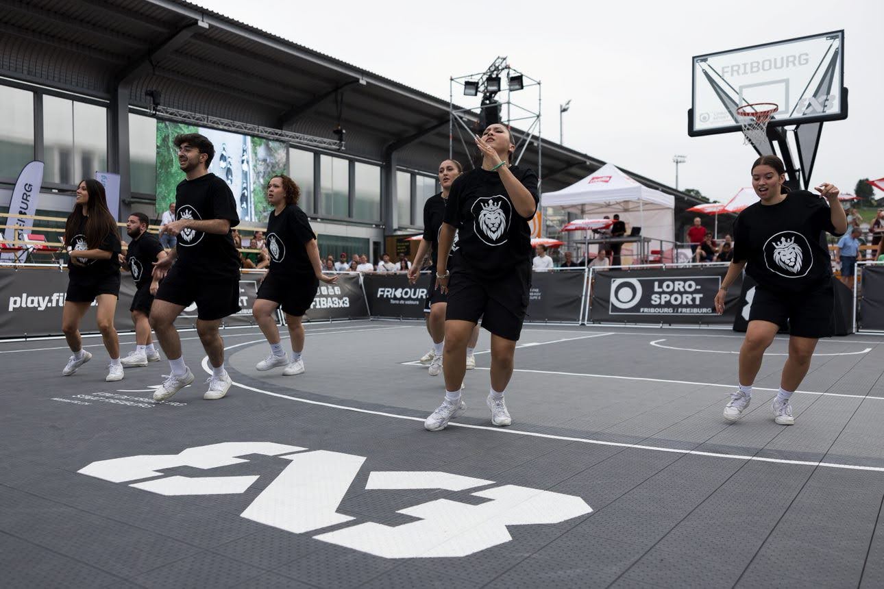 Des danseurs exécutant une chorégraphie sur un terrain de basket 3x3 à Fribourg.