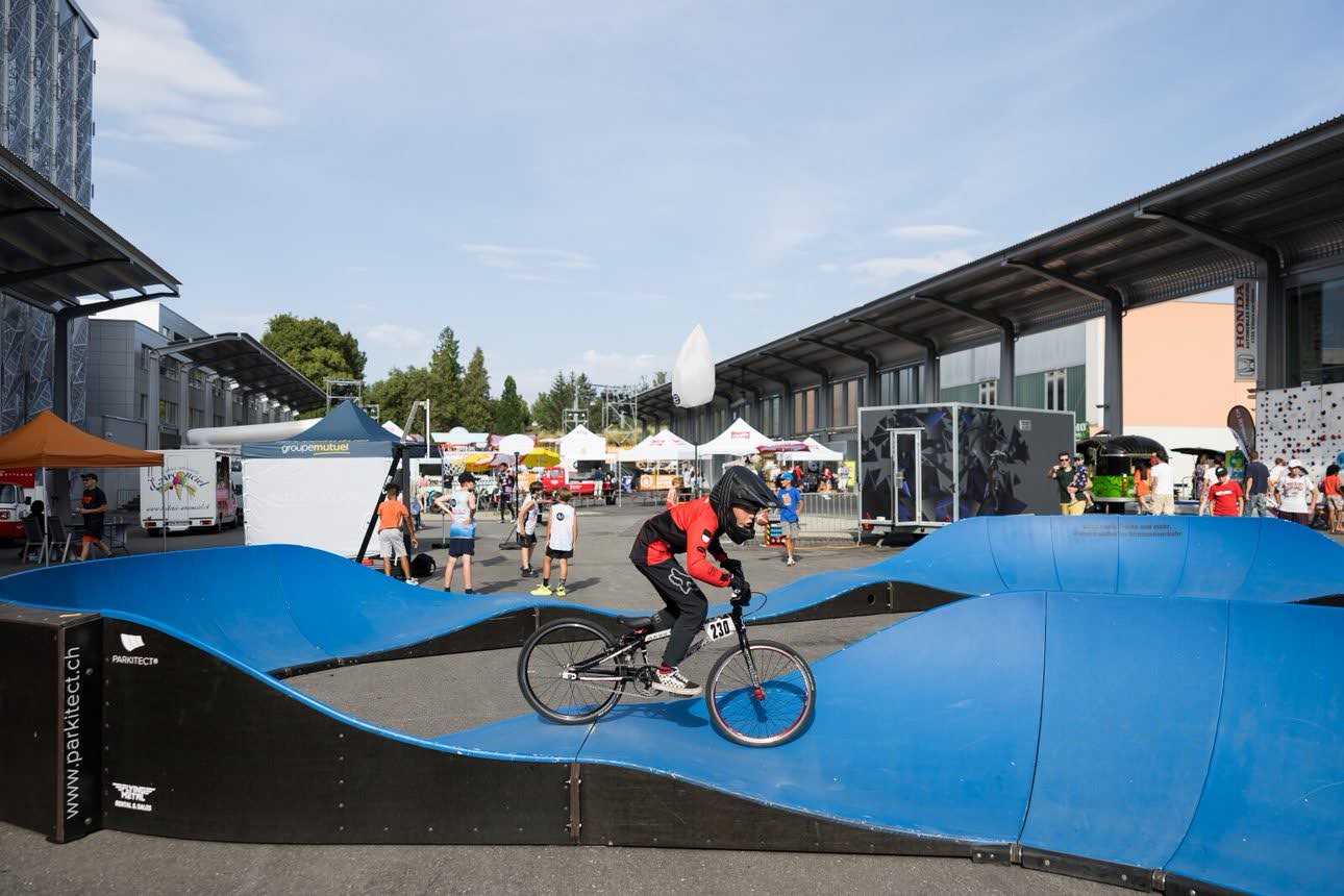 Un cycliste roulant sur une pump track lors d'un événement sportif en plein air.